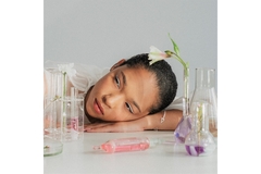 A female model poses with a chemistry set decorated with flowers, representing natural skin care science.